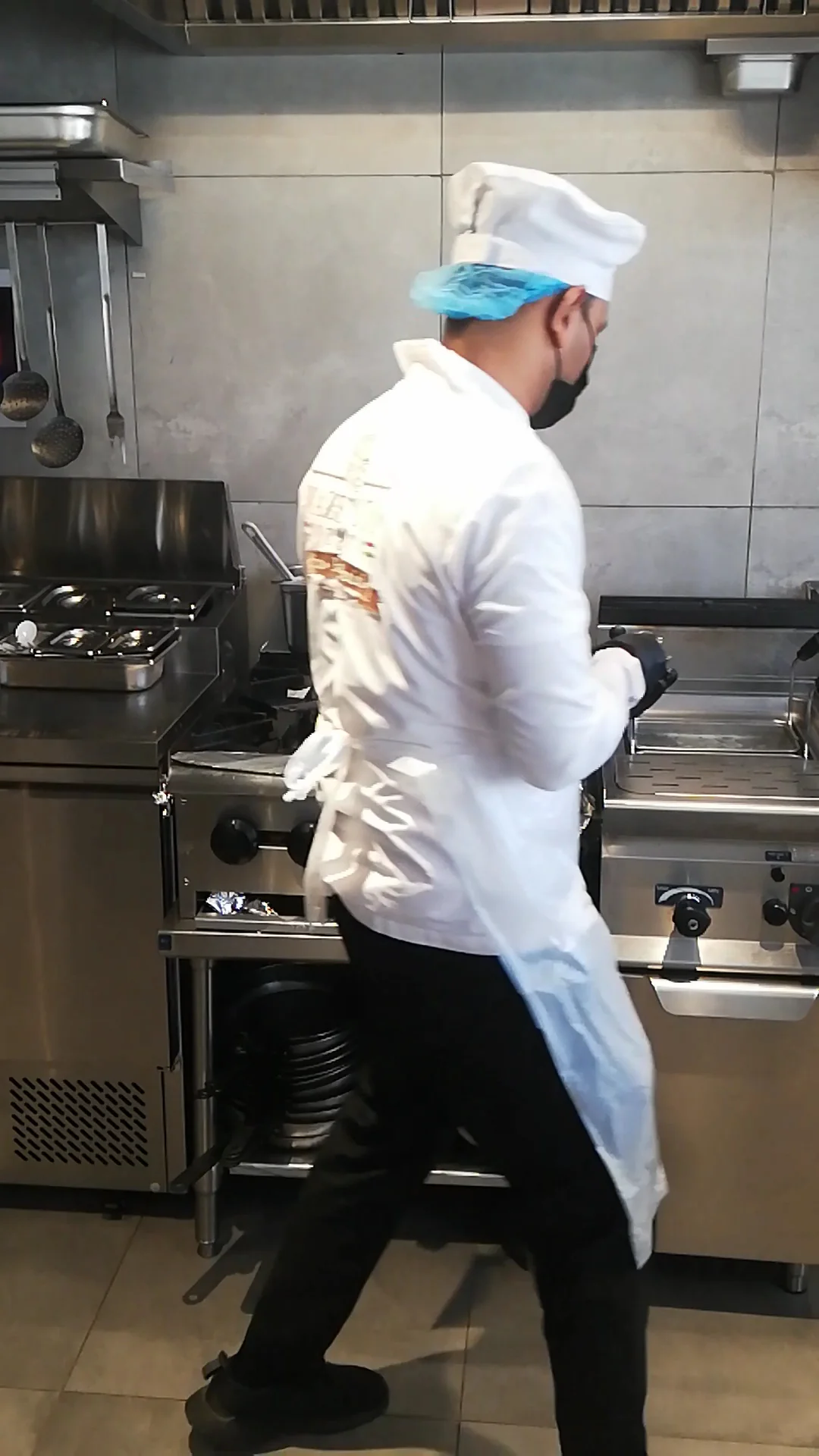 Chef in uniform walking through the open kitchen