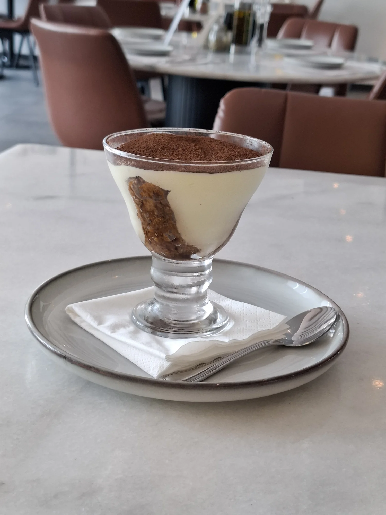 Layered mascarpone dessert in a glass with cocoa dust